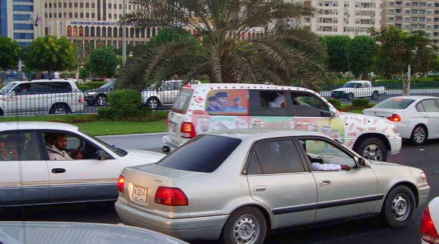Parked cars with palm trees and modern buildings in Abu Dhabi urban setting during daytime