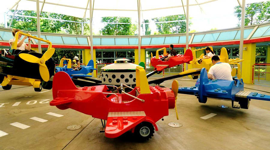 Legoland Malaysia Children riding colorful airplane-themed rides in an indoor hangar at Legoland Malaysia theme park
