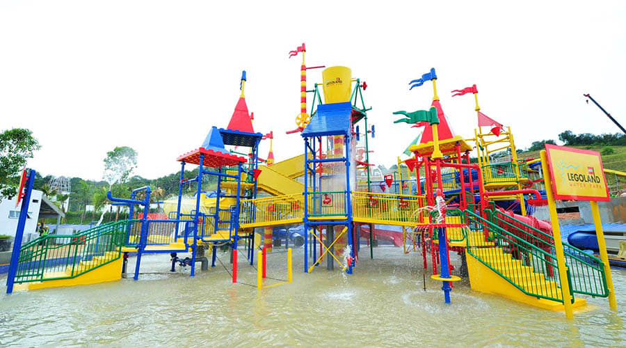 Legoland Malaysia Colorful Legoland Malaysia water play structure with blue, red, and yellow towers and slides surrounded by water during flood