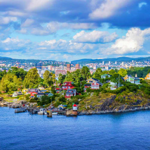 Waterfront residential neighborhood in Oslo, Norway with colorful houses on rocky peninsula overlooking blue water and city s