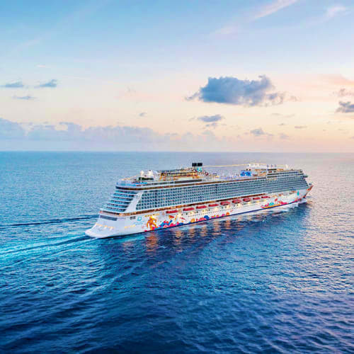 Large modern cruise ship sailing on calm turquoise ocean water at sunset with clouds in sky