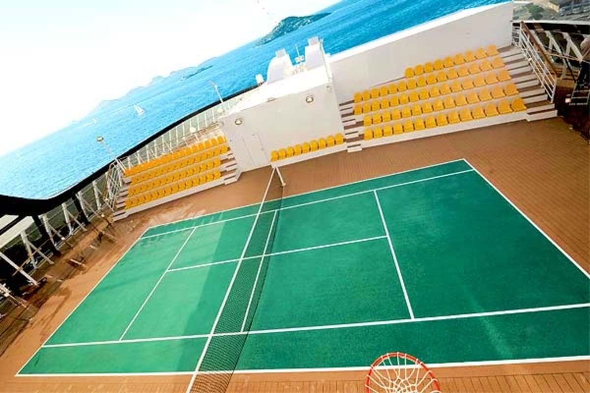 MSC Fantasia Canary Islands Escape Cruise ship deck with green tennis court, yellow seating, ocean and coastline visible in background