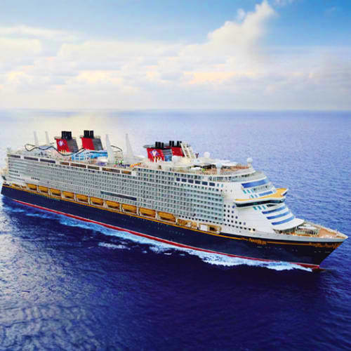 Large Disney cruise ship sailing on open blue ocean under partly cloudy sky