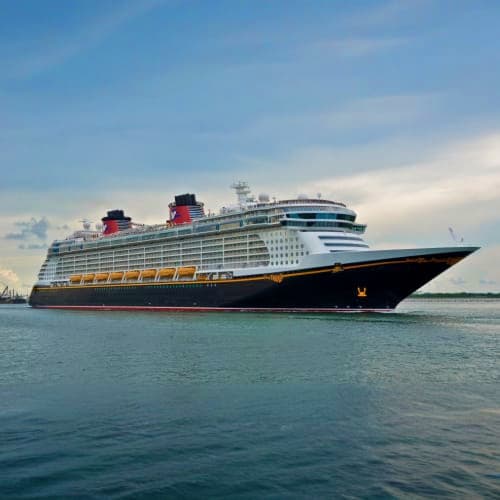 Large modern cruise ship with white upper decks and black hull sailing on calm blue water under cloudy sky
