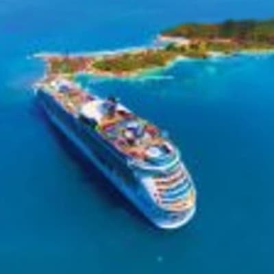 Aerial view of Navigator of the Seas cruise ship anchored near a tropical island in turquoise blue waters