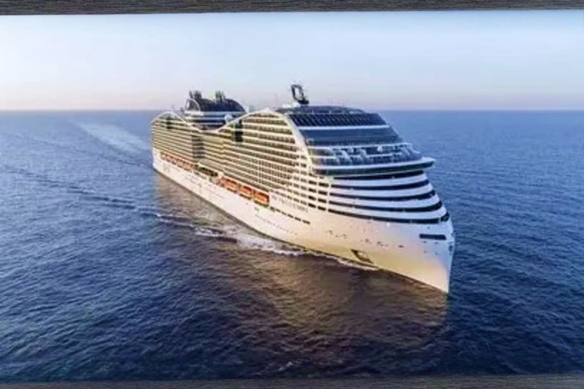 Modern cruise ship with white hull and dark striping sailing on calm blue ocean waters