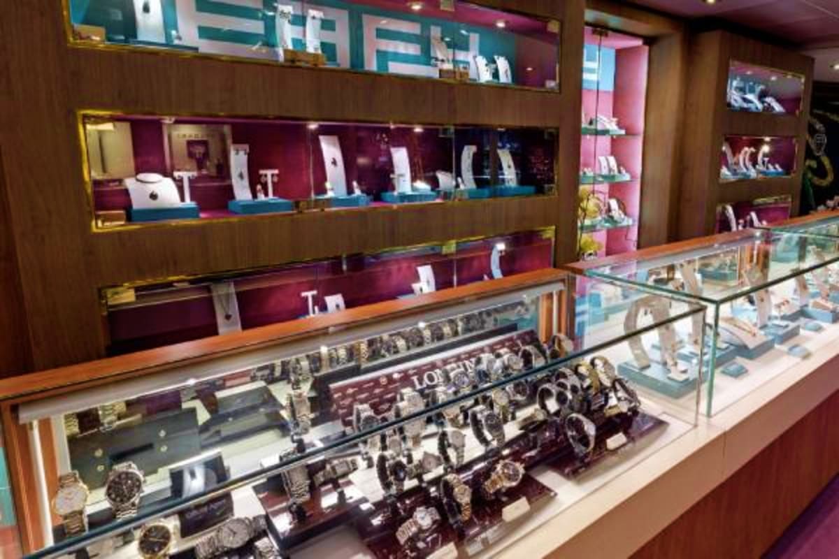 Interior of luxury jewelry store with glass display cases showcasing watches, rings, and accessories under warm lighting
