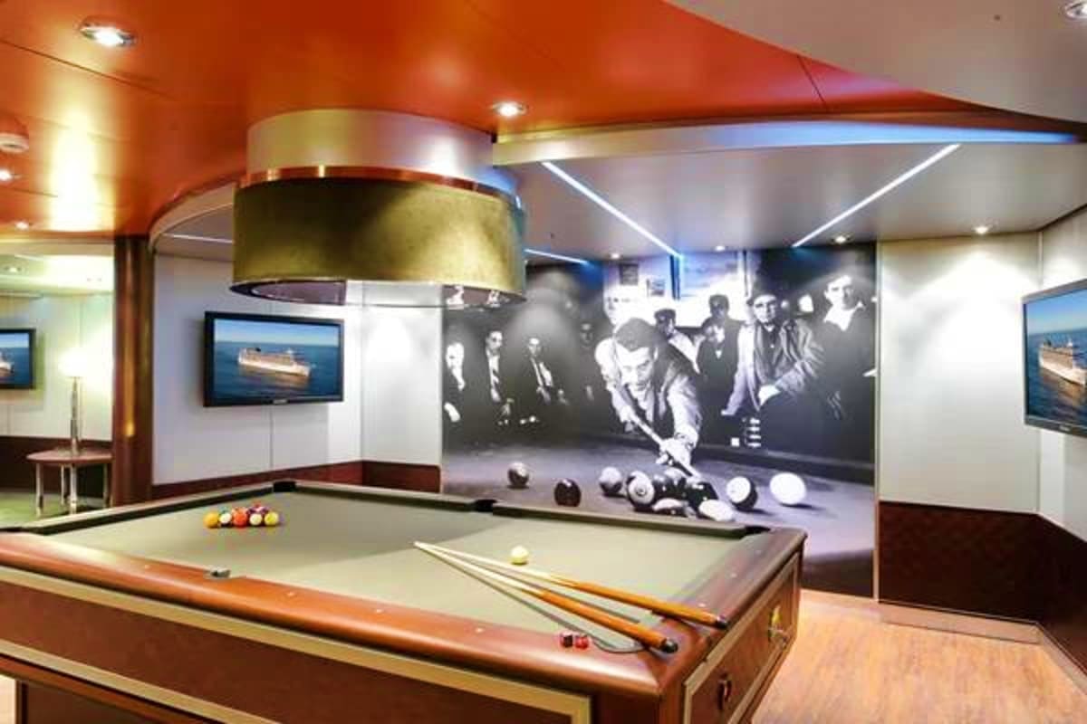 Modern billiards room on cruise ship with pool table, brass pendant light, vintage black and white photographs on wall, and o