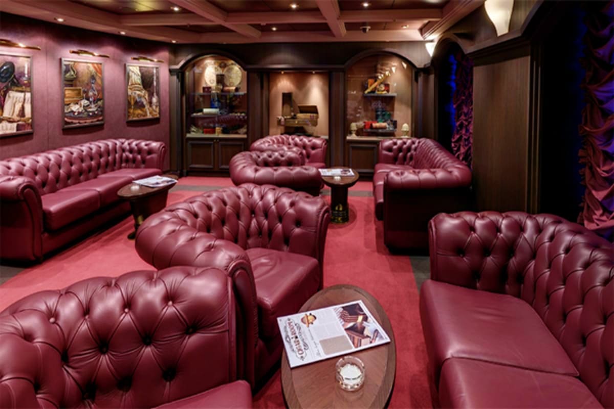 Luxurious wine-colored leather Chesterfield seating in an upscale cruise ship lounge with illuminated display cases and mahog