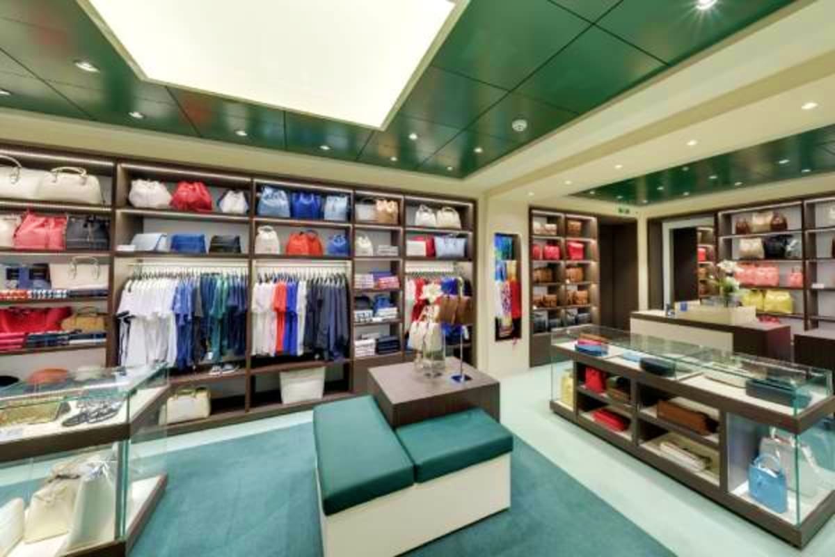 Modern retail clothing store interior with display shelves, hanging garments, and glass counters showcasing merchandise