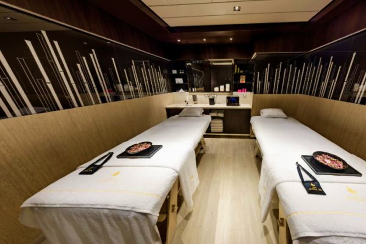Modern spa treatment room on MSC Euribia cruise ship with two massage beds, black hot stone plates, and contemporary dark woo