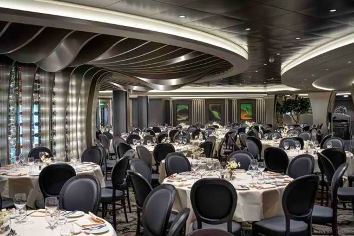 Elegant main dining room on MSC Euribia cruise ship with round tables, white linens, black chairs, and modern curved ceiling 