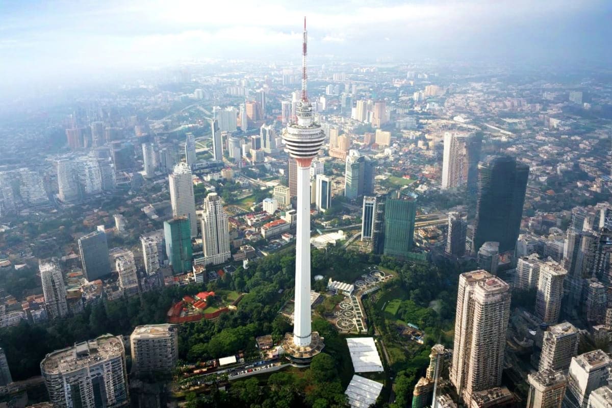Aerial view of Kuala Lumpur Tower surrounded by city skyline and green parkland areas