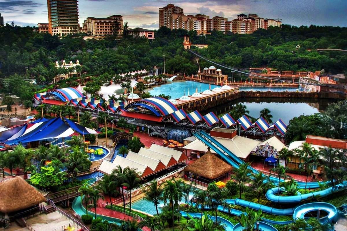 Aerial view of Sunway Lagoon water park in Malaysia with blue slides, pools, and resort buildings surrounded by lush green la