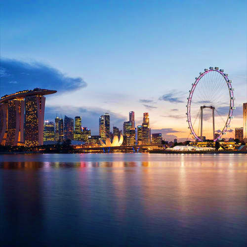 Singapore skyline at dusk featuring Marina Bay Sands hotel, illuminated skyscrapers, and the Singapore Flyer observation whee