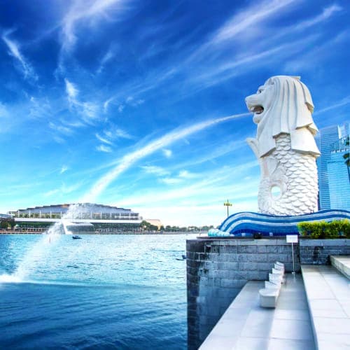 Merlion statue overlooking Marina Bay with modern buildings and blue sky in Singapore