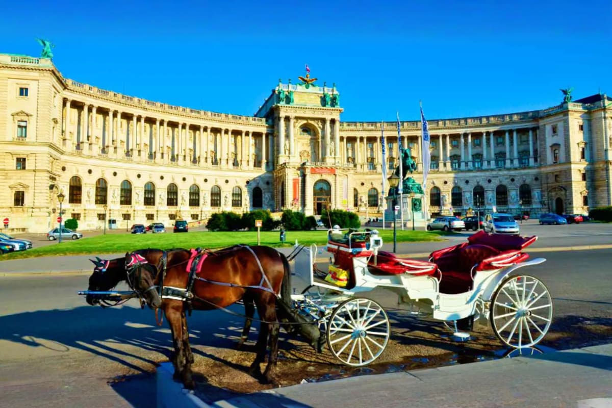 Horse-drawn carriage with red canopy in front of Hofburg Palace in Vienna, Austria on sunny day