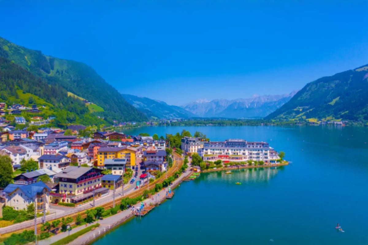 Aerial view of an Alpine lake town with colorful buildings, turquoise water, and mountain landscape in Austria