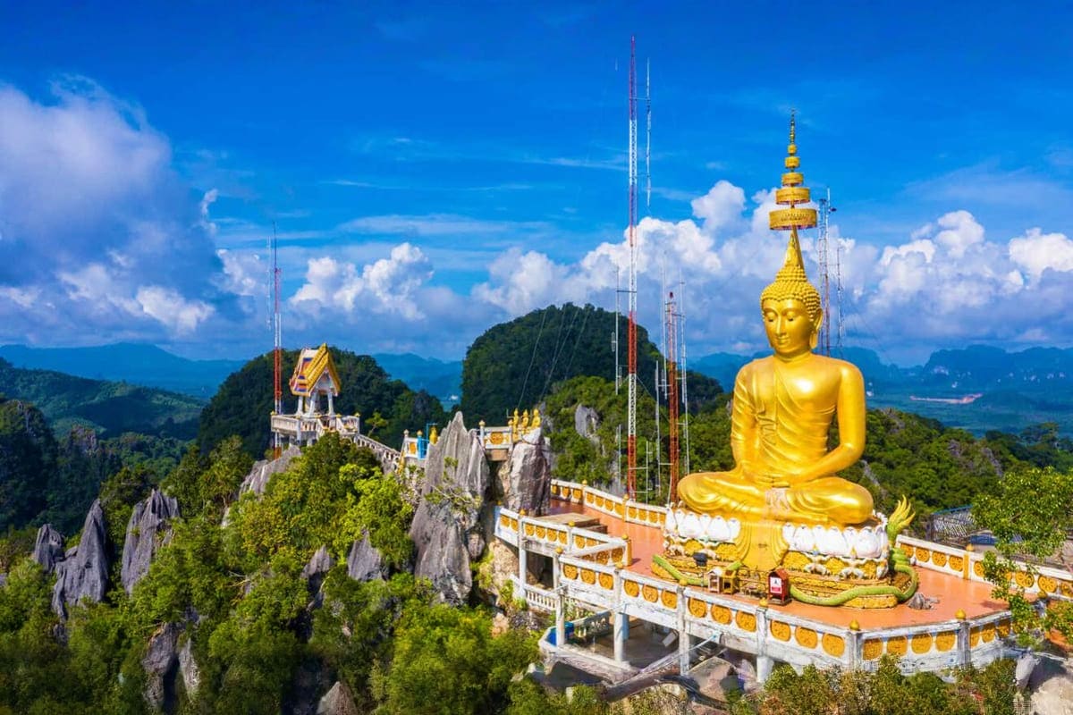 Krabi City Tour Golden Buddha statue overlooking Krabi mountains and temples with lush green forested landscape and blue sky