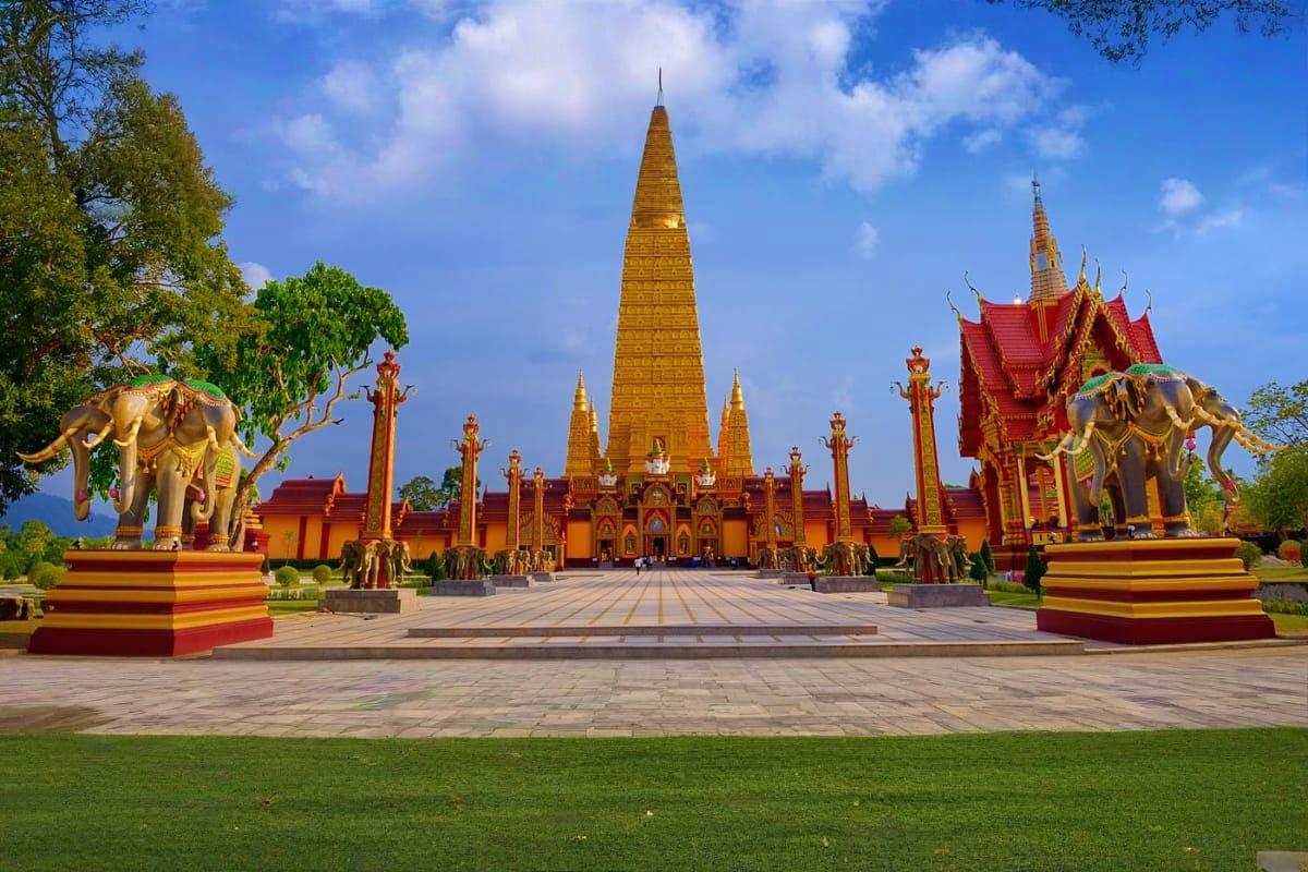 Krabi City Tour Golden Buddhist temple with golden elephant statues and red-roofed buildings under blue sky in Krabi, Thailand