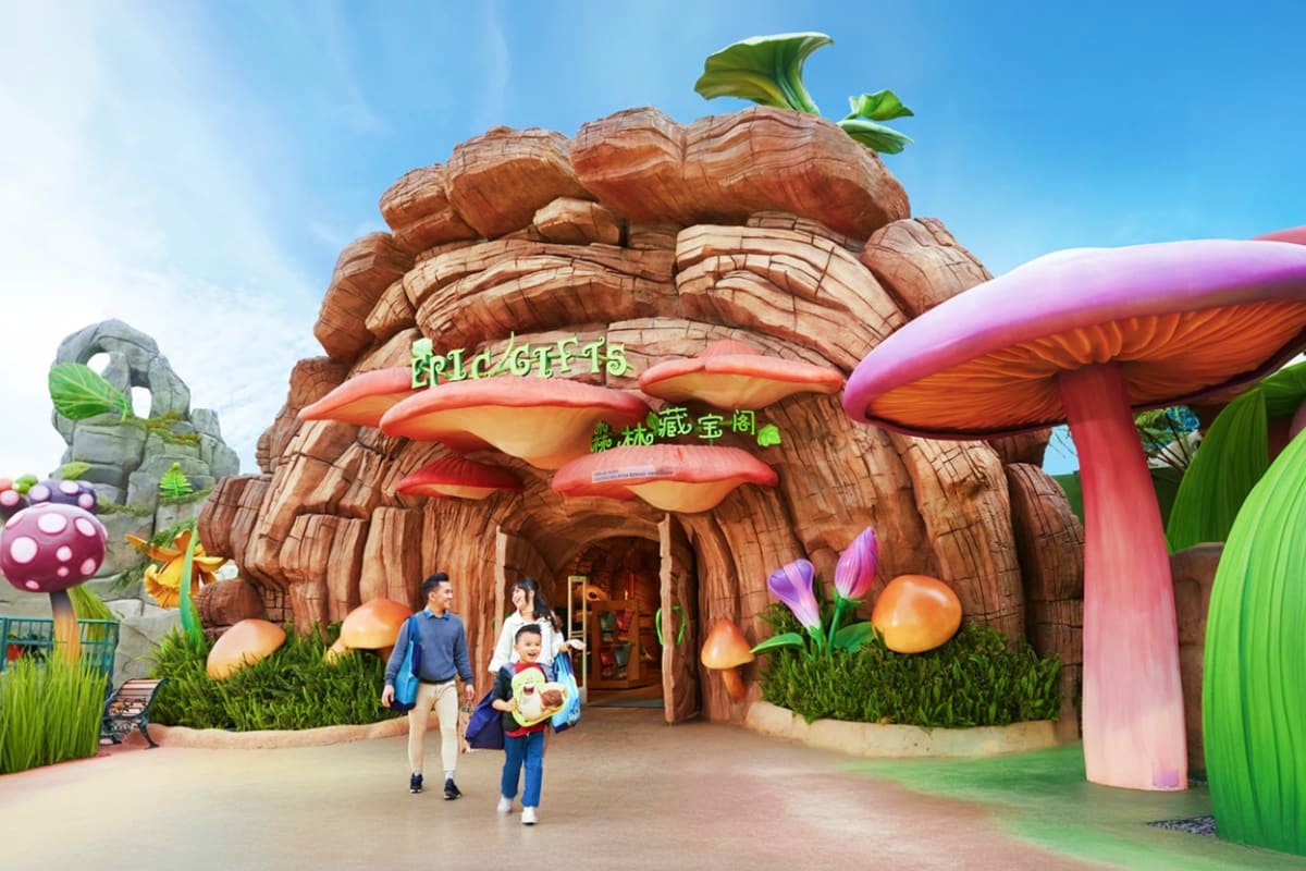 Family walking through giant mushroom-shaped entrance at Skyworld theme park with colorful oversized mushrooms and toadstools