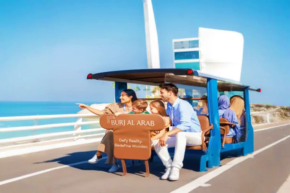 Guided Inside Burj Al Arab Open Dated Tickets Family on blue tram tour overlooking Burj Al Arab and Arabian Gulf coastline in Dubai
