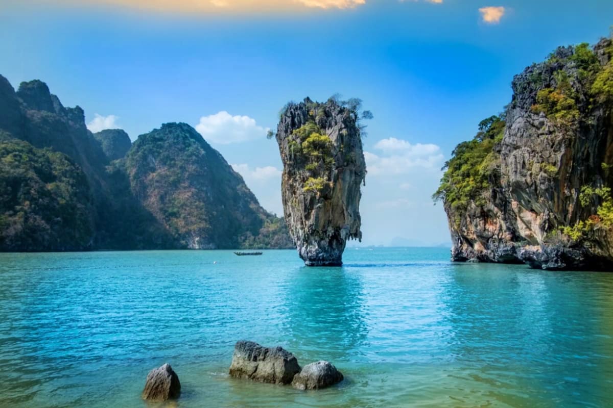 James Bond Island on Speed Boat Khao Phing Kan limestone rock formation rising from turquoise waters with surrounding cliffs and boats in Phang Nga Bay, Thai