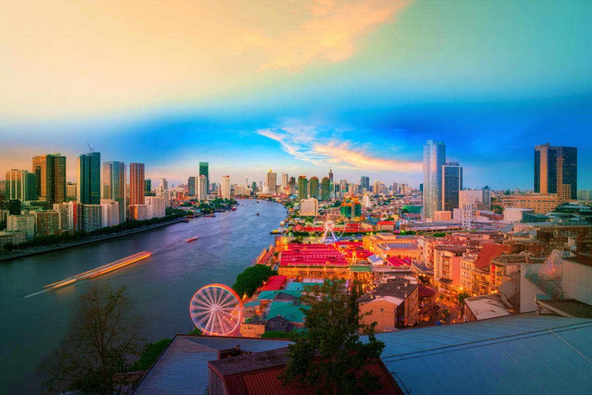 Aerial sunset view of New York City with illuminated Ferris wheel, East River, and Manhattan skyline at dusk