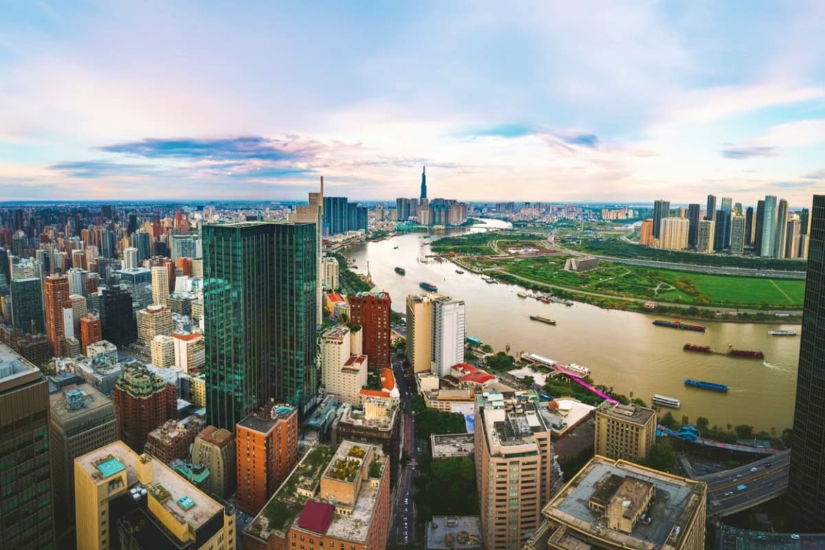 Aerial view of Ho Chi Minh City skyline with Saigon River, showing dense urban buildings and waterway with boats