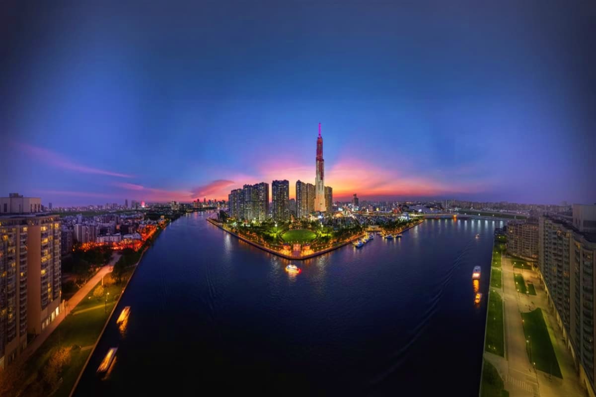 Aerial twilight view of Landmark 81 tower illuminated above the Saigon River with surrounding cityscape and residential build