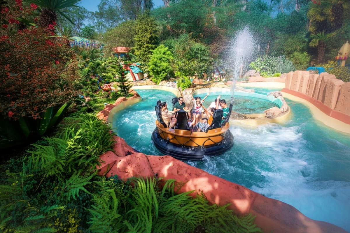 Guests riding a spinning water ride boat at VinWonders Grand Park Ho Chi Minh, surrounded by lush tropical vegetation and the