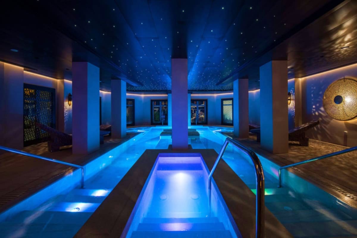 Modern spa pool with starlit ceiling, glowing blue water channels, and illuminated columns inside MSC World Europa cruise shi