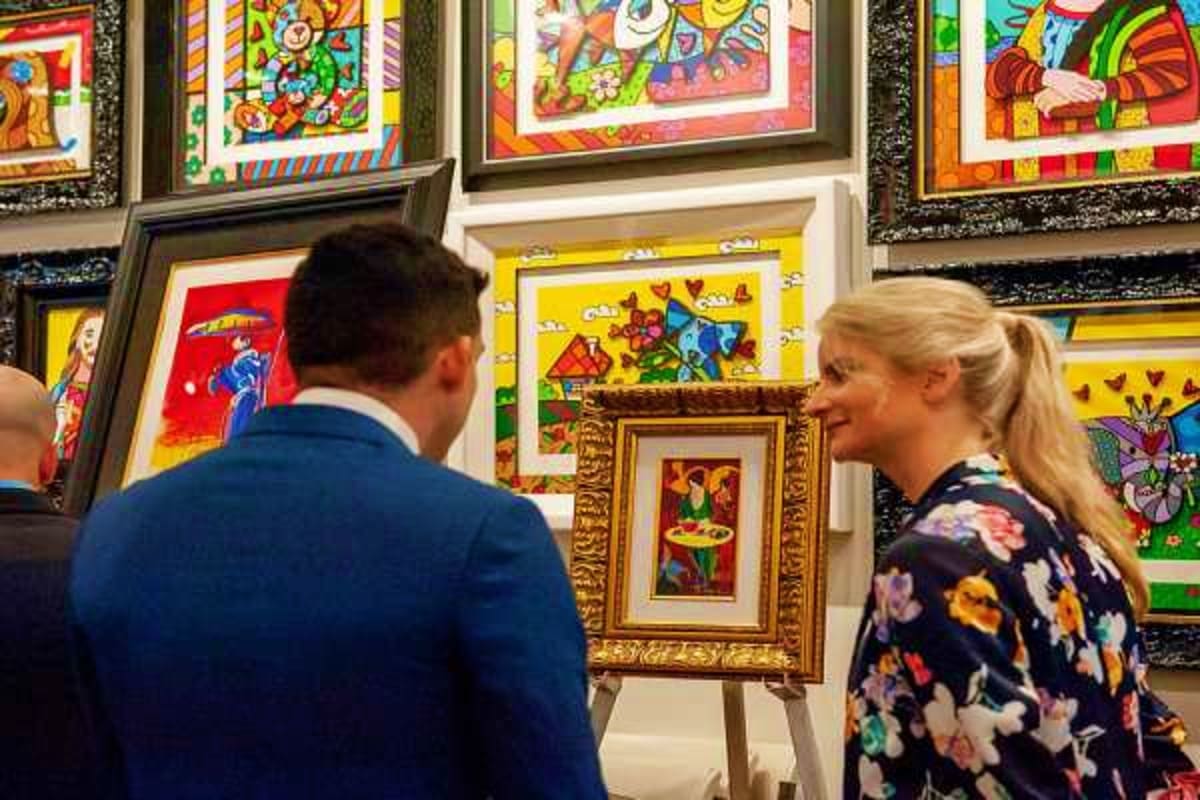 Man and woman viewing colorful framed pop art paintings in an art gallery or exhibition space