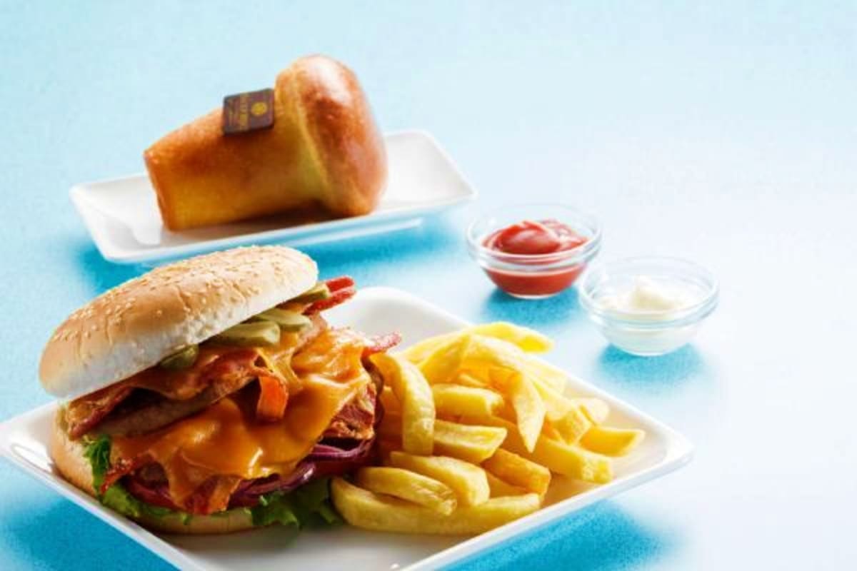 Assorted fast food items including cheeseburger, French fries, pastry, and condiment cups on blue background