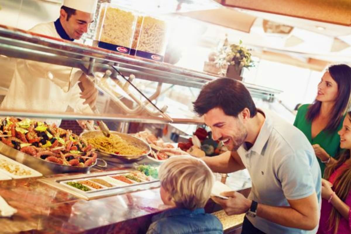 Family ordering food at a buffet counter on Costa Diadema cruise ship with pasta and other dishes displayed