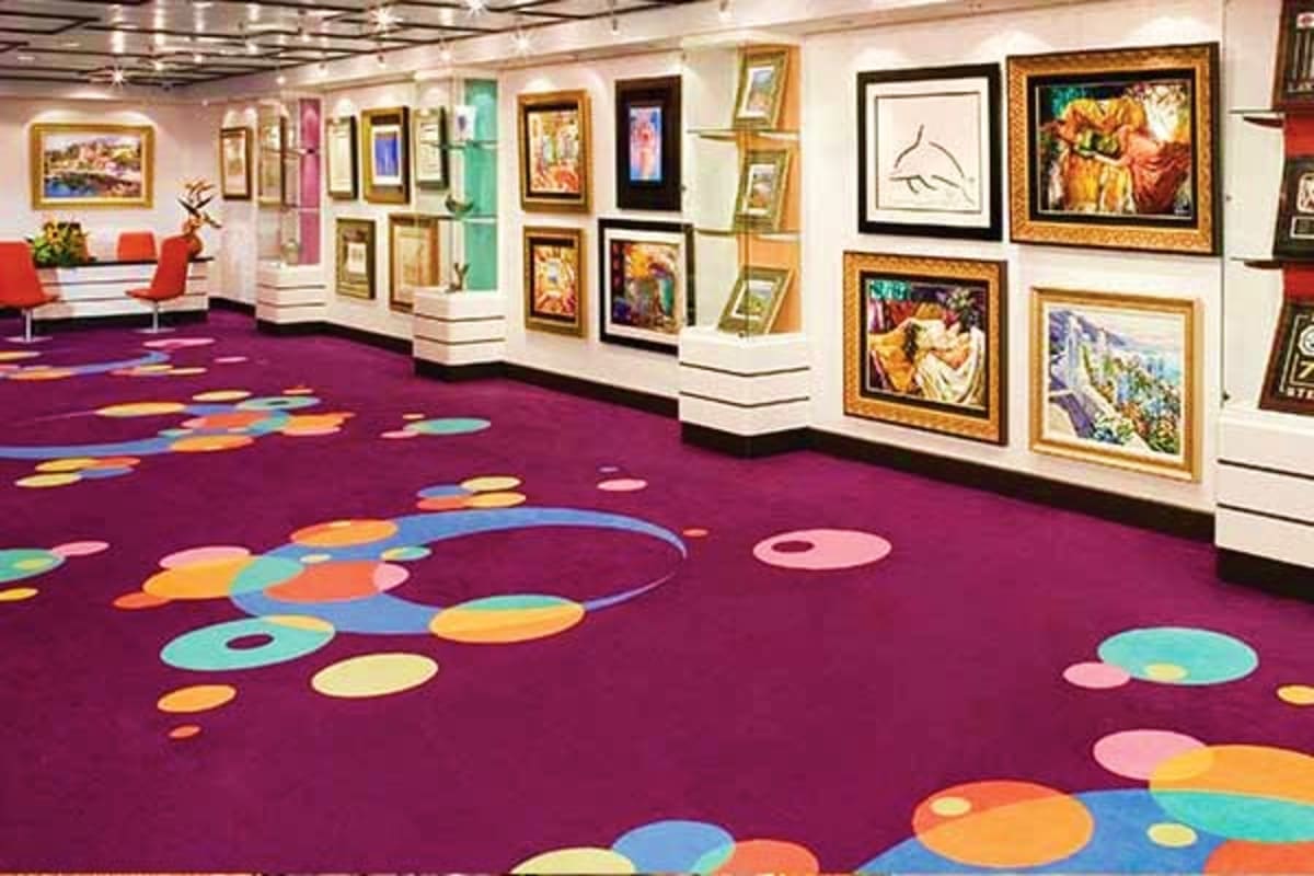Modern art gallery interior with purple carpet featuring colorful circular pattern design and framed artwork displayed on whi