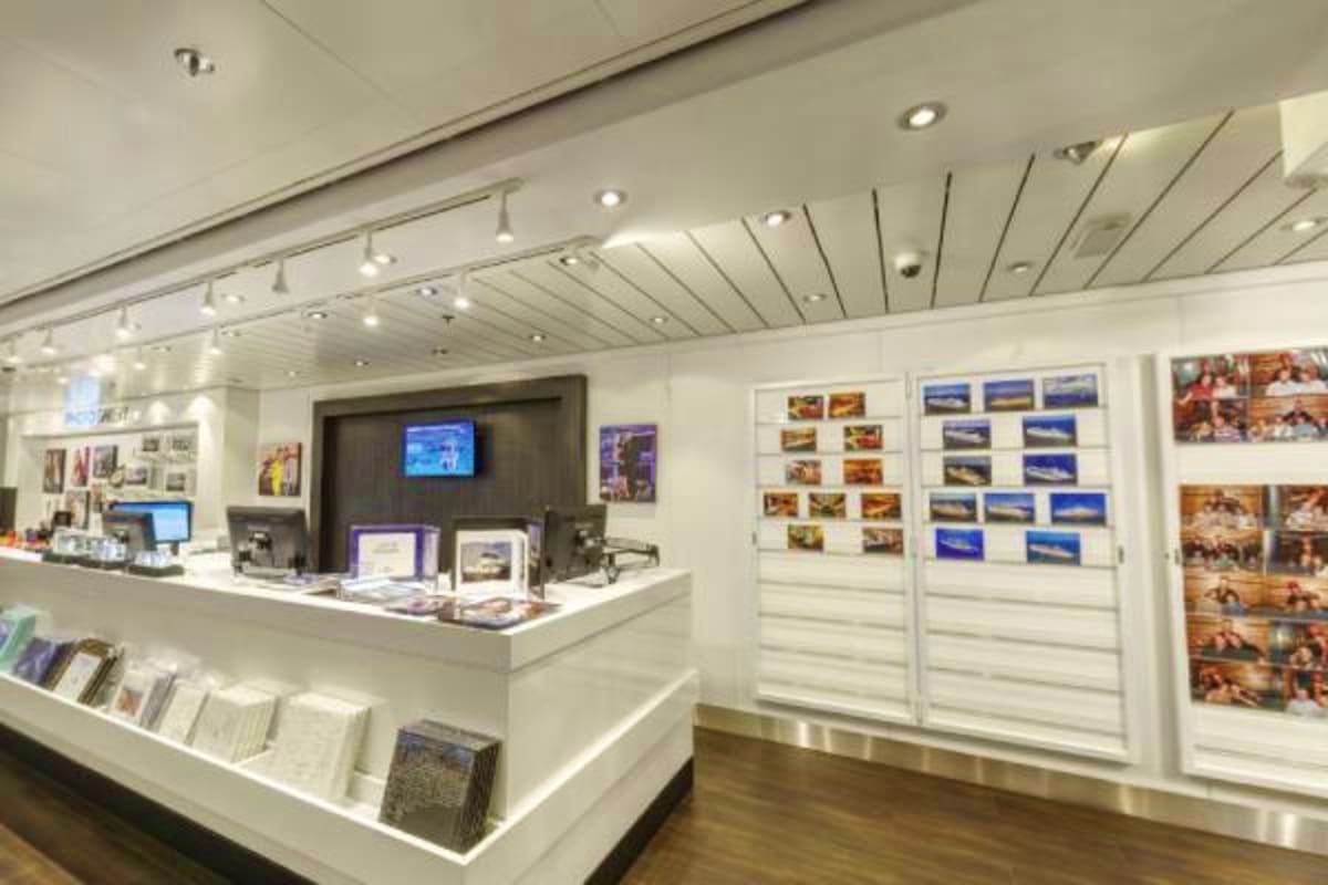 Modern cruise ship interior travel agency or onboard shop with white counters, photo displays of Japan destinations, and rece