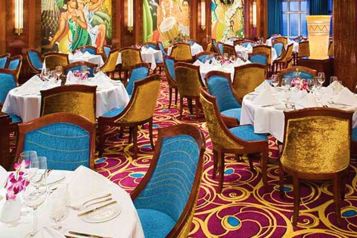 Elegant dining room with gold and blue upholstered chairs, white tablecloths, colorful patterned carpet, and decorative mural
