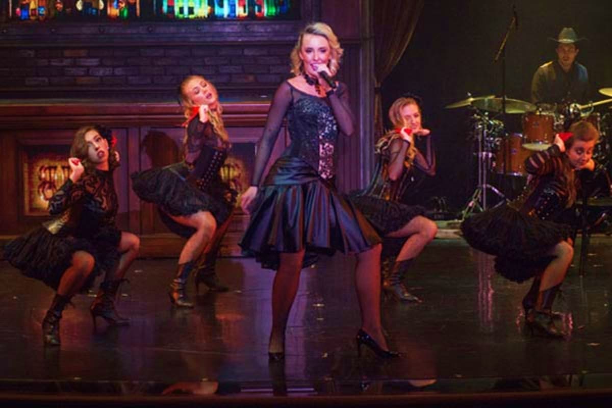 Female performer in black sequined dress singing on stage with backup dancers and live band during Norwegian Jade entertainme