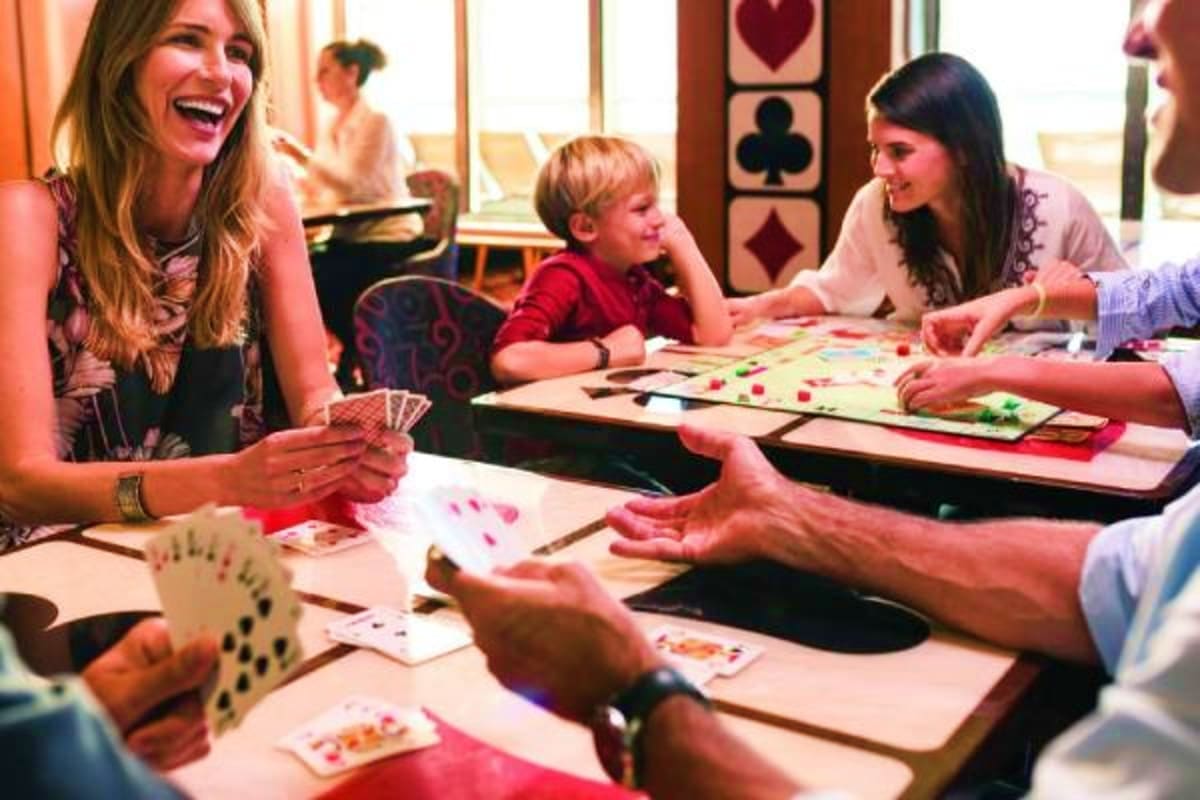 Family playing card games together at a table during a Costa Fascinosa cruise activity