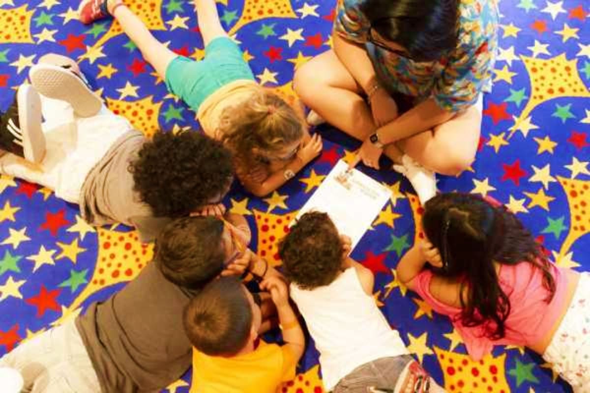 Adult and children sitting in circle on colorful star-patterned floor during interactive activity or game on cruise ship