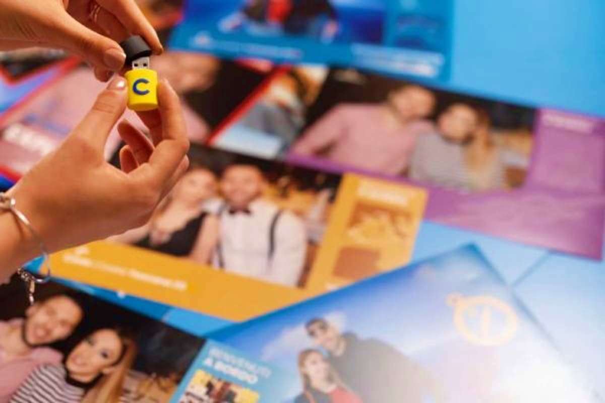 Hand holding yellow LEGO brick with letter C above Costa Fascinosa cruise brochures and promotional materials