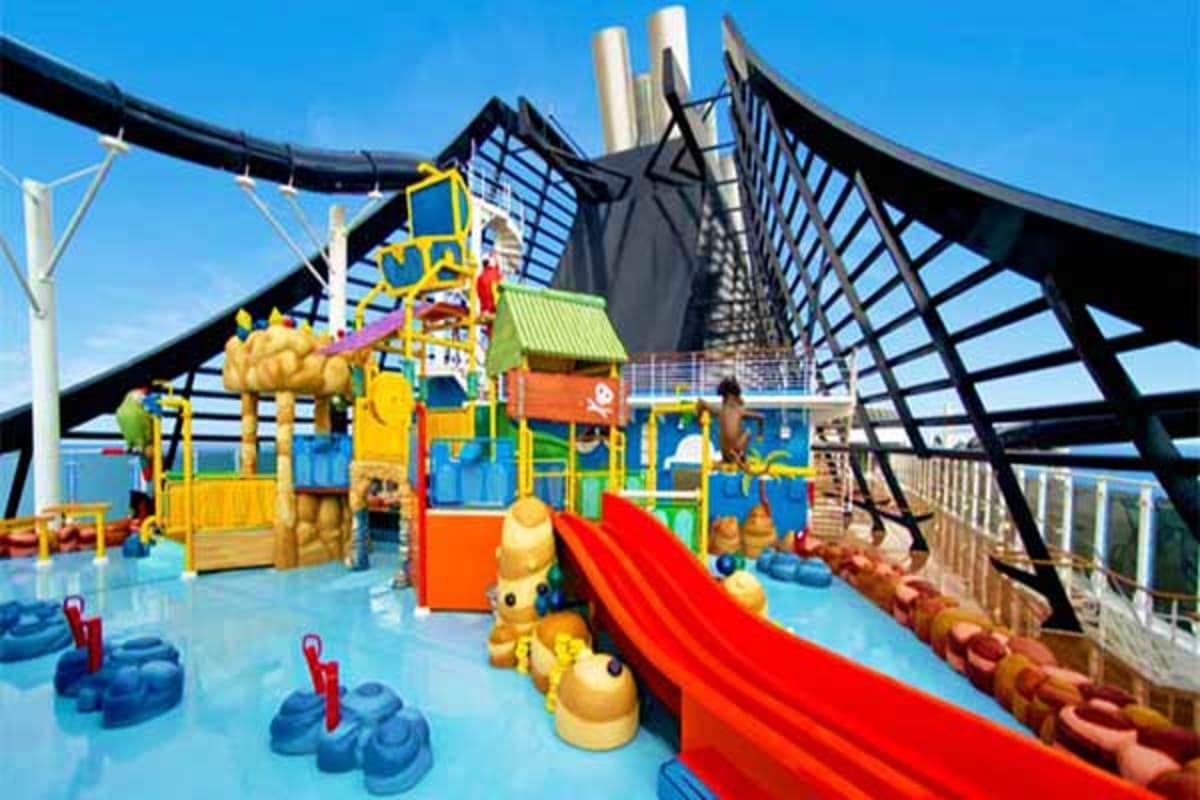 Colorful children's water play area on cruise ship deck with slides, interactive water features, and ocean view