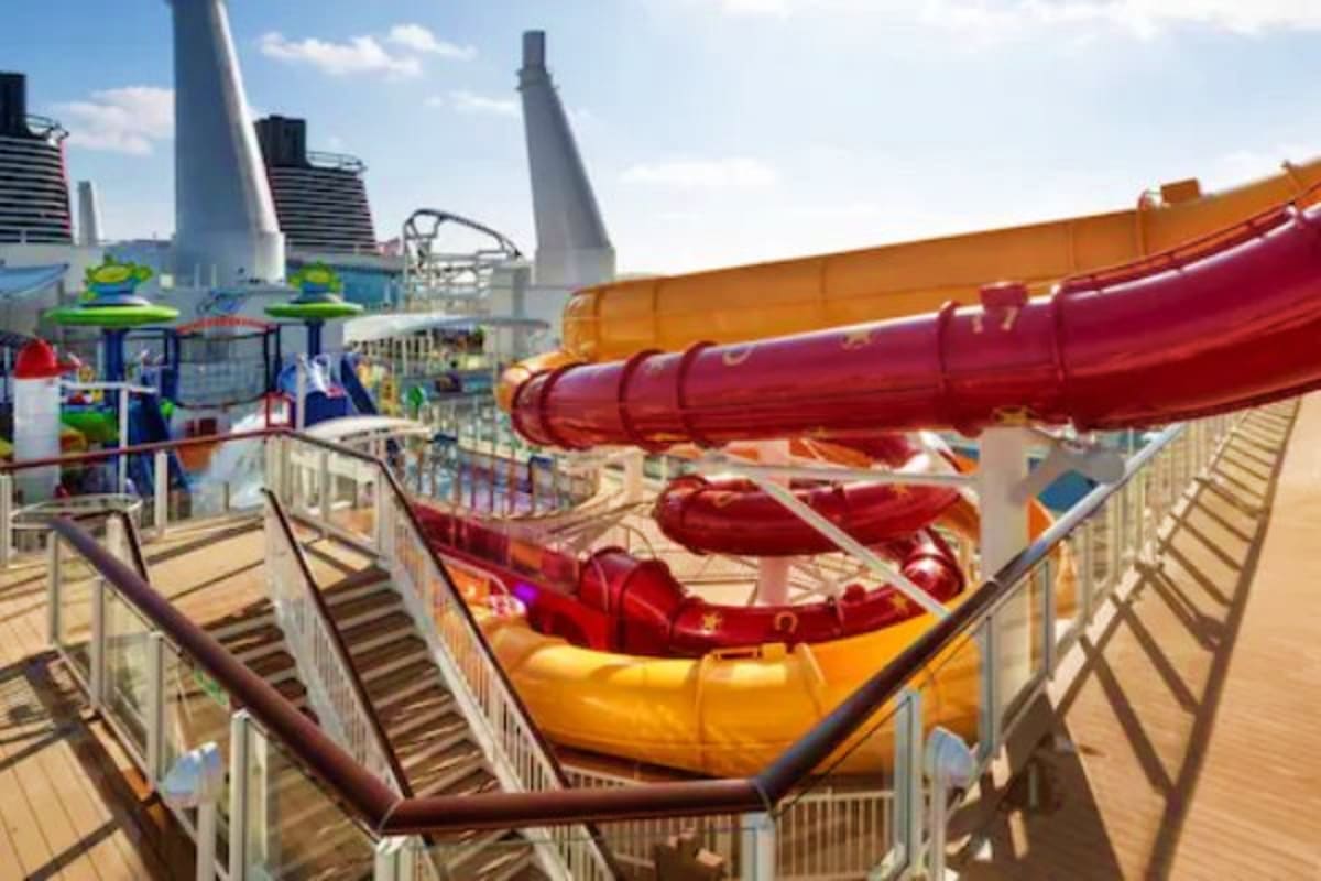 Cruise ship waterslide with red and yellow tubes overlooking city skyline with modern buildings