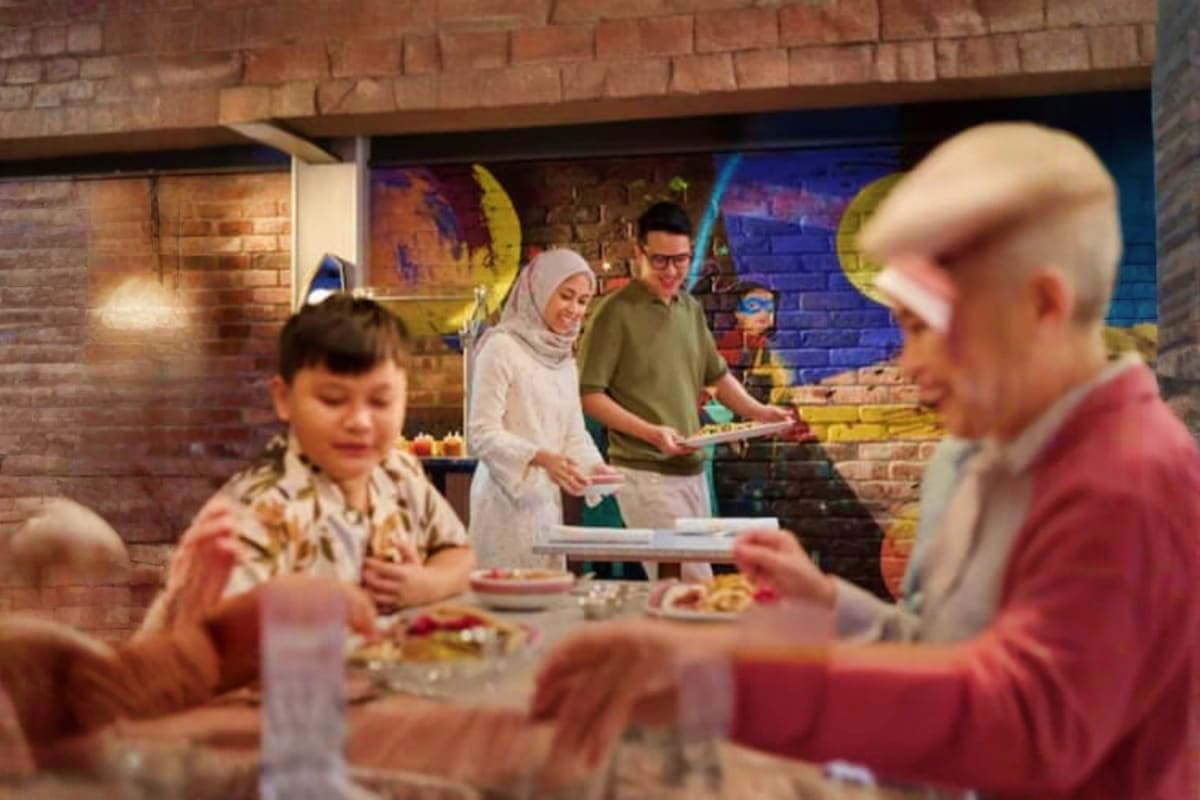 Multicultural family enjoying food together at outdoor dining table with colorful mural artwork on brick wall background