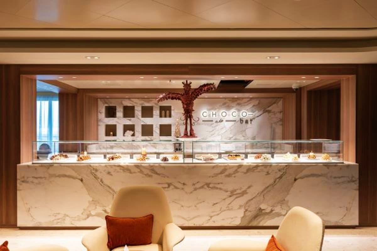 Luxury chocolate bar storefront with marble counter, display cases, and modern wood and stone interior design