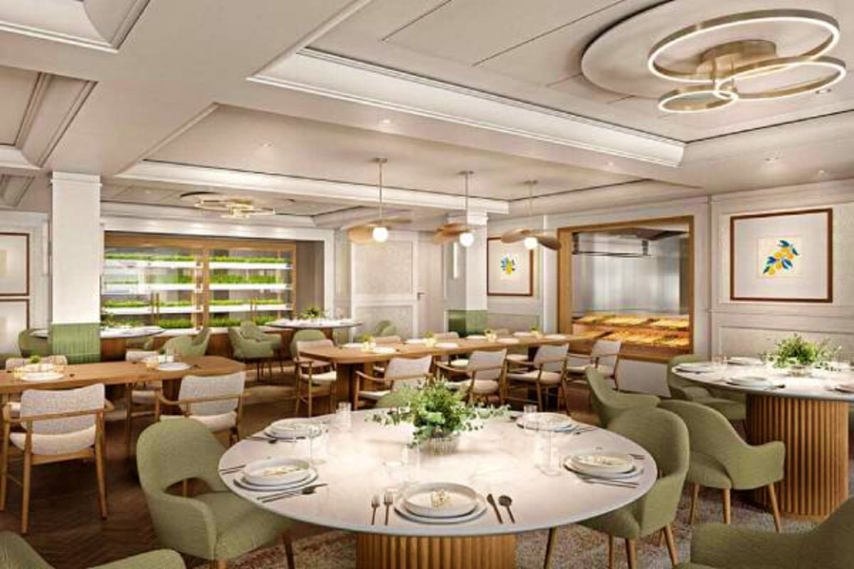 Modern restaurant dining room with round white tables, green upholstered chairs, wood accents, and large windows overlooking 