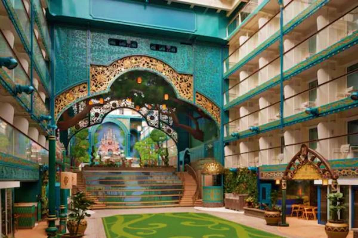 Ornate turquoise gateway with golden filigree arch framing a distant temple, flanked by residential buildings in an Asian-ins