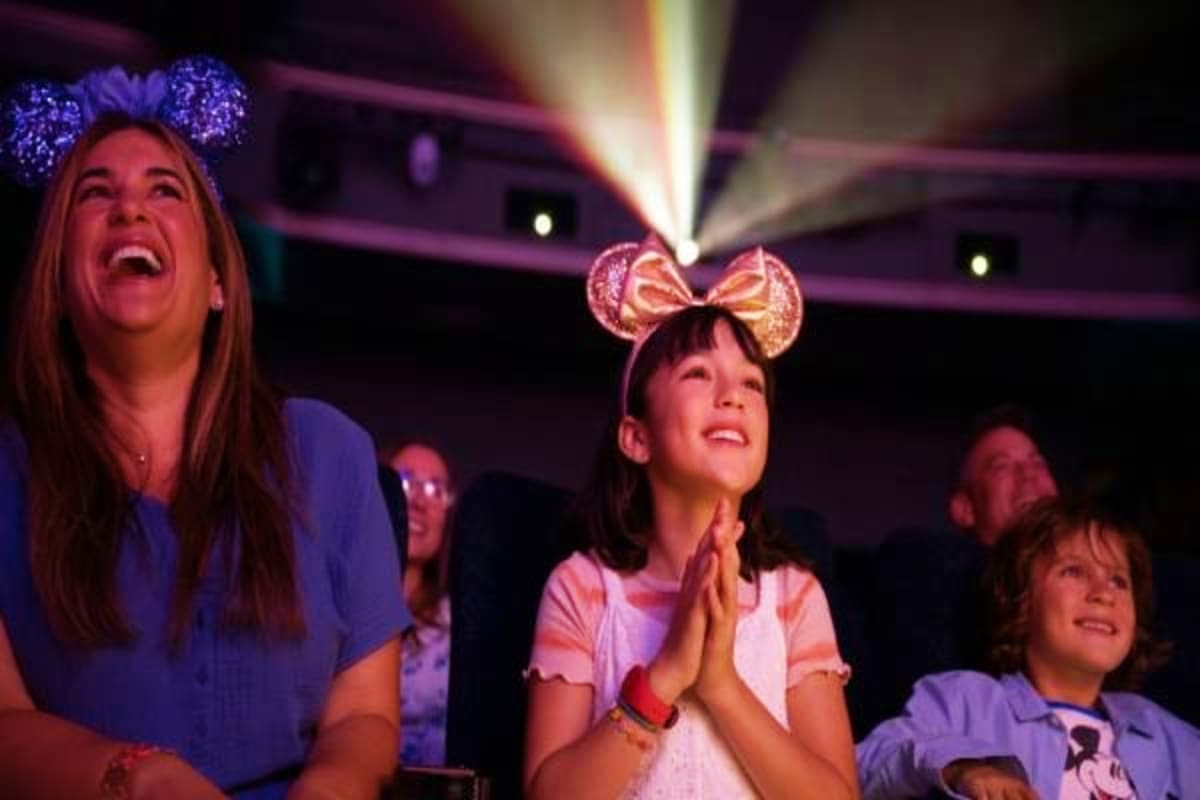 Family wearing Mickey Mouse ears watching magical light show at Disney theme park in Asia