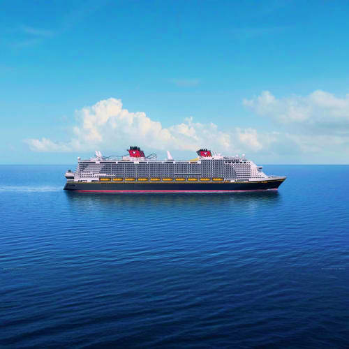Disney cruise ship sailing on calm blue ocean water under clear sky with white clouds